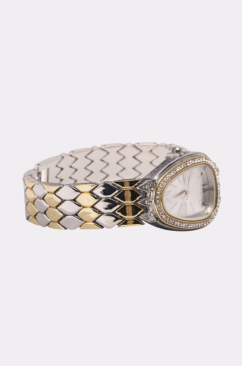 The LUXE LIVING WATCH features a mixed-metal silver and gold bracelet, an oval crystal-bordered face, and a minimalist numberless dial for modern elegance. 2