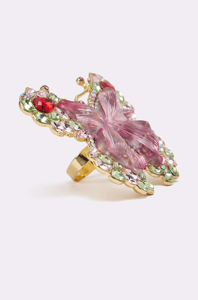 The SPREAD YOUR WINGS RING showcases a large gold butterfly design with pink, green, and clear gemstones, centered by a pink glass butterfly on a white background. 4