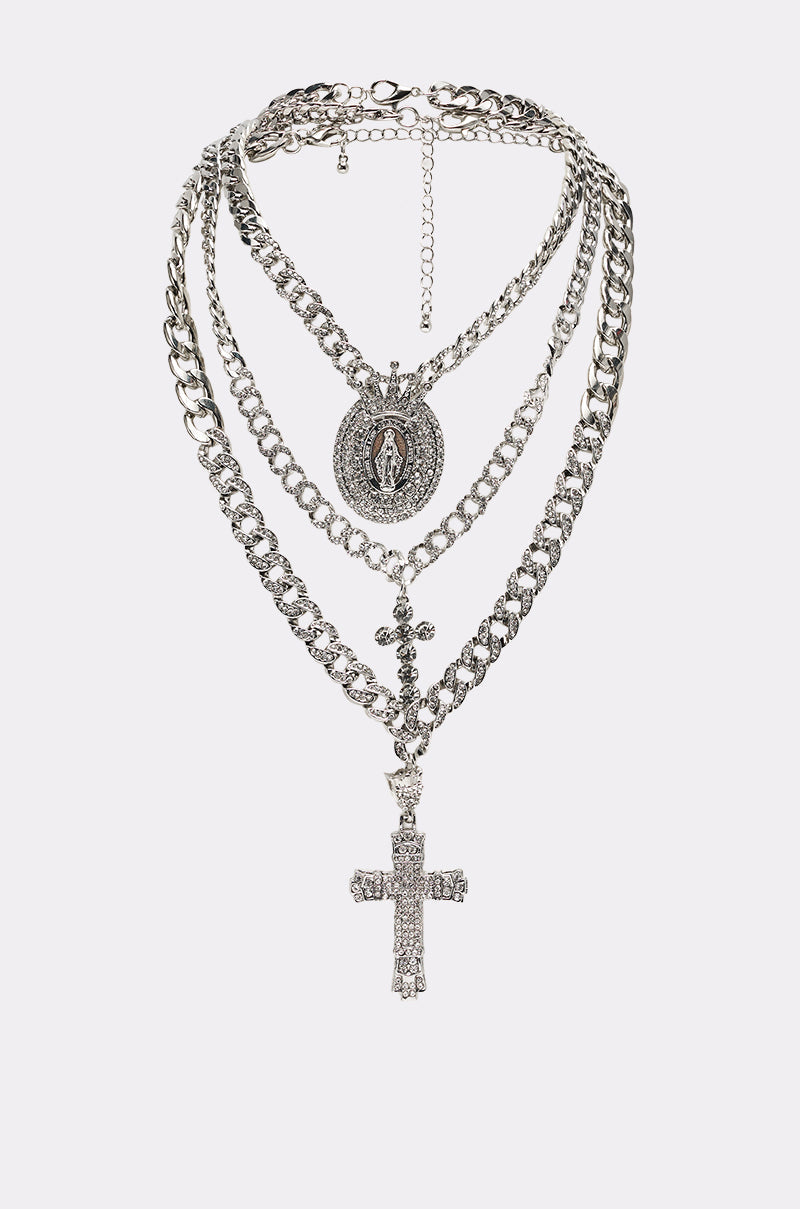 The PRAY FOR YOU NECKLACE SET is a layered silver chain with two pendants: an oval Virgin Mary medallion and an ornate rhinestone cross, shown on a plain white background. 0
