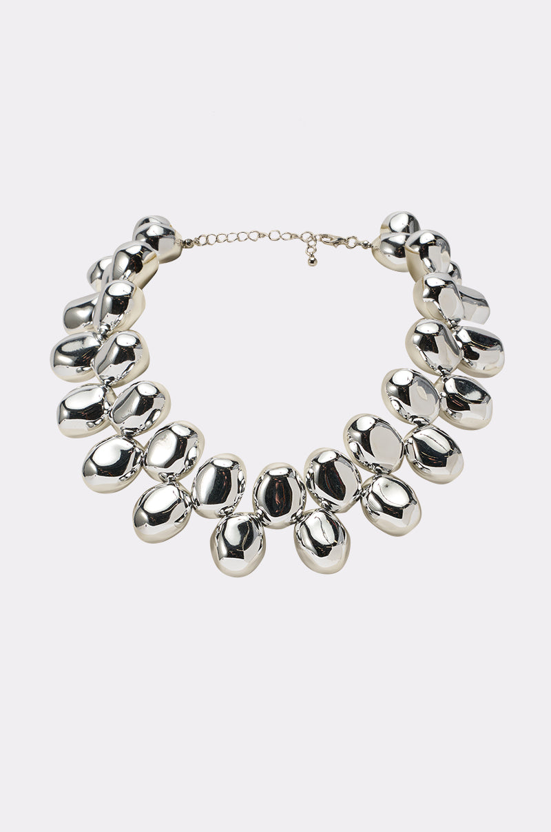 The CAME A LONG WAY NECKLACE is a silver statement piece with large, smooth oval beads linked together and finished with a delicate adjustable chain clasp, shown on a plain white background. 0