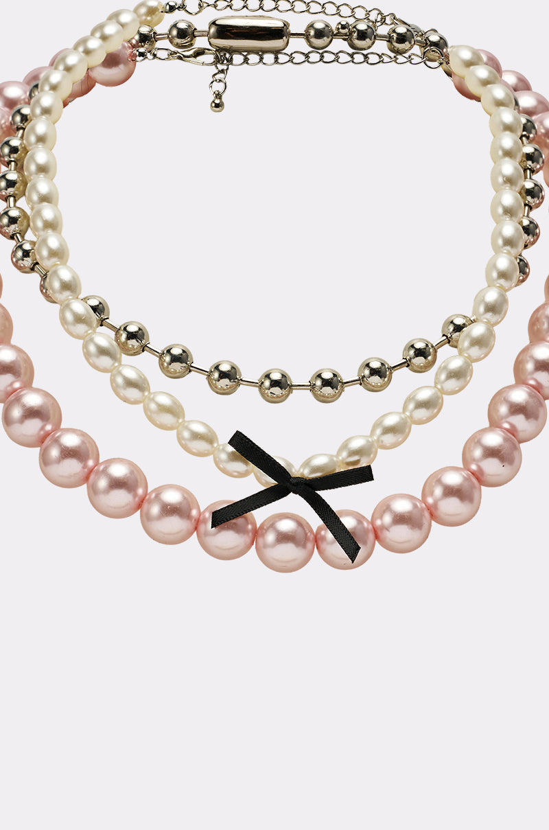 The GWEN NECKLACE SET features large pink pearls with a black bow, medium white pearls, and small silver beads—an elegant feminine piece with a silver clasp and extender chain. 3