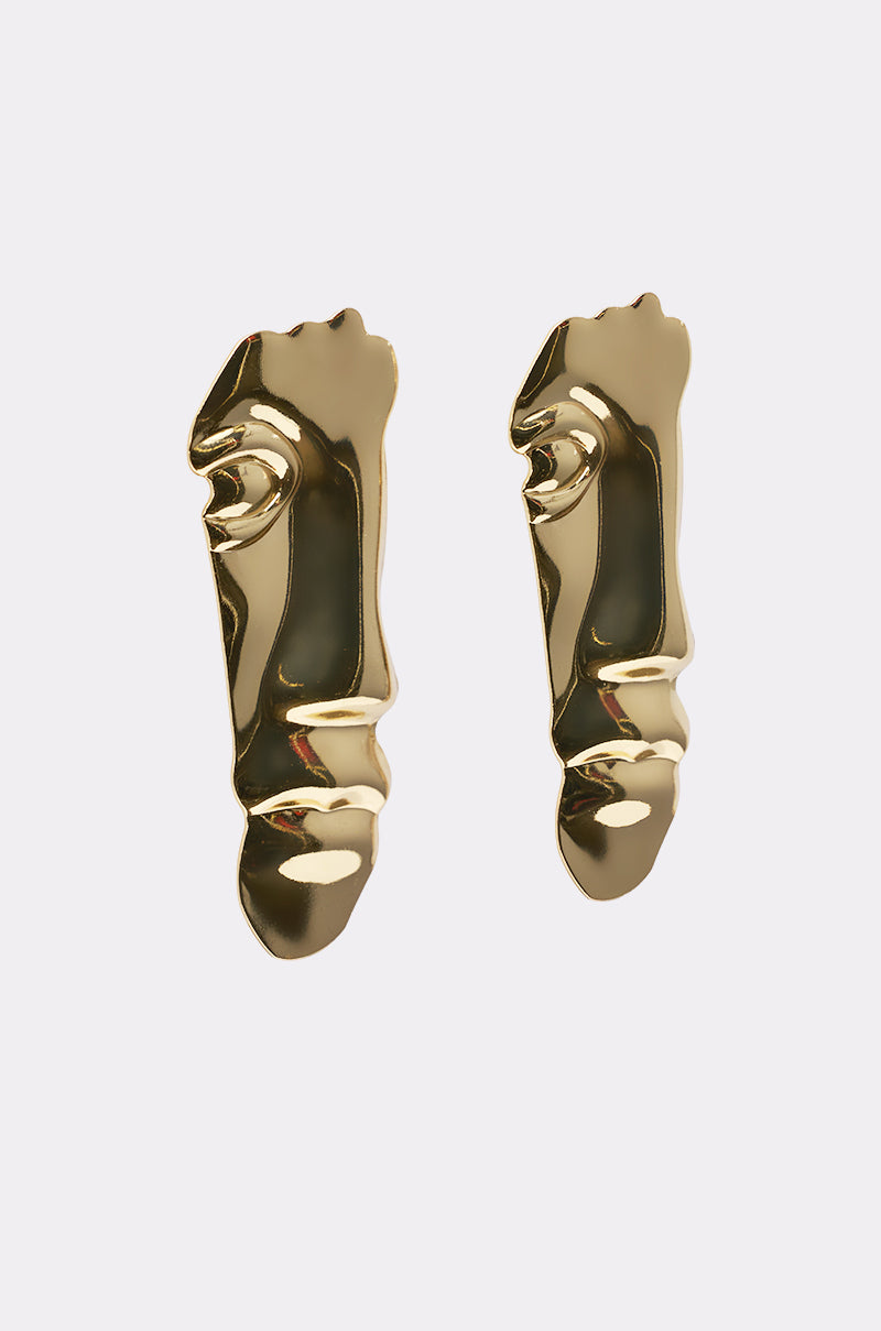 The 2FACE EARRING features shiny gold-tone abstract human faces with prominent noses, lips, and eyes, displayed against a plain white background. 2