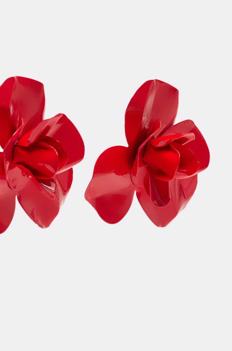 Close-up of two shiny, crimson GALA EARRING pieces with layered petals on a plain, light background. These floral earrings, shaped like flowers, are partially visible at the left and right edges. 3