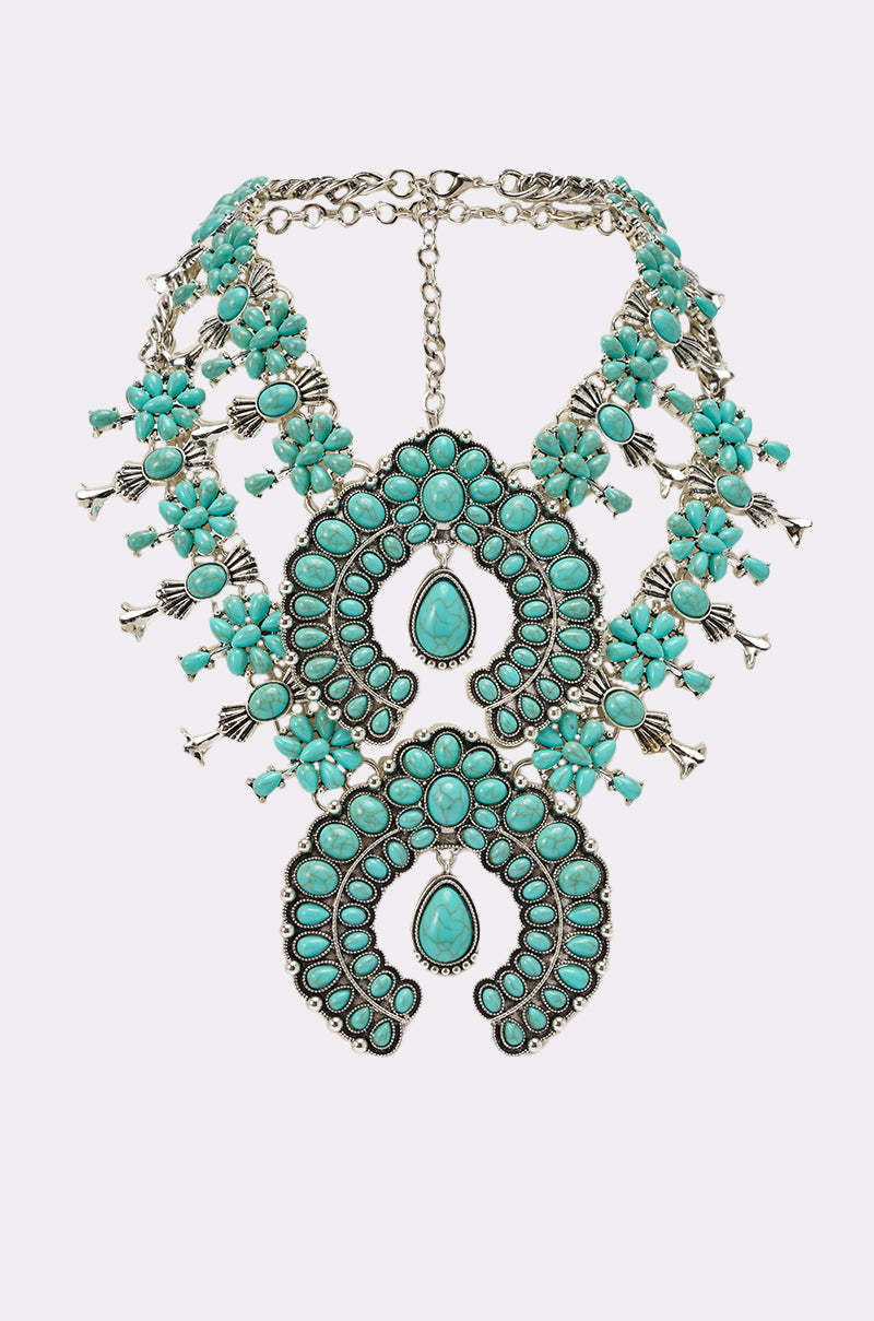The HERE FOR THE VIBES NECKLACE is a bold western statement piece with two large turquoise crescent-shaped pendants, silver accents, multiple turquoise beads, and an adjustable chain clasp. 1