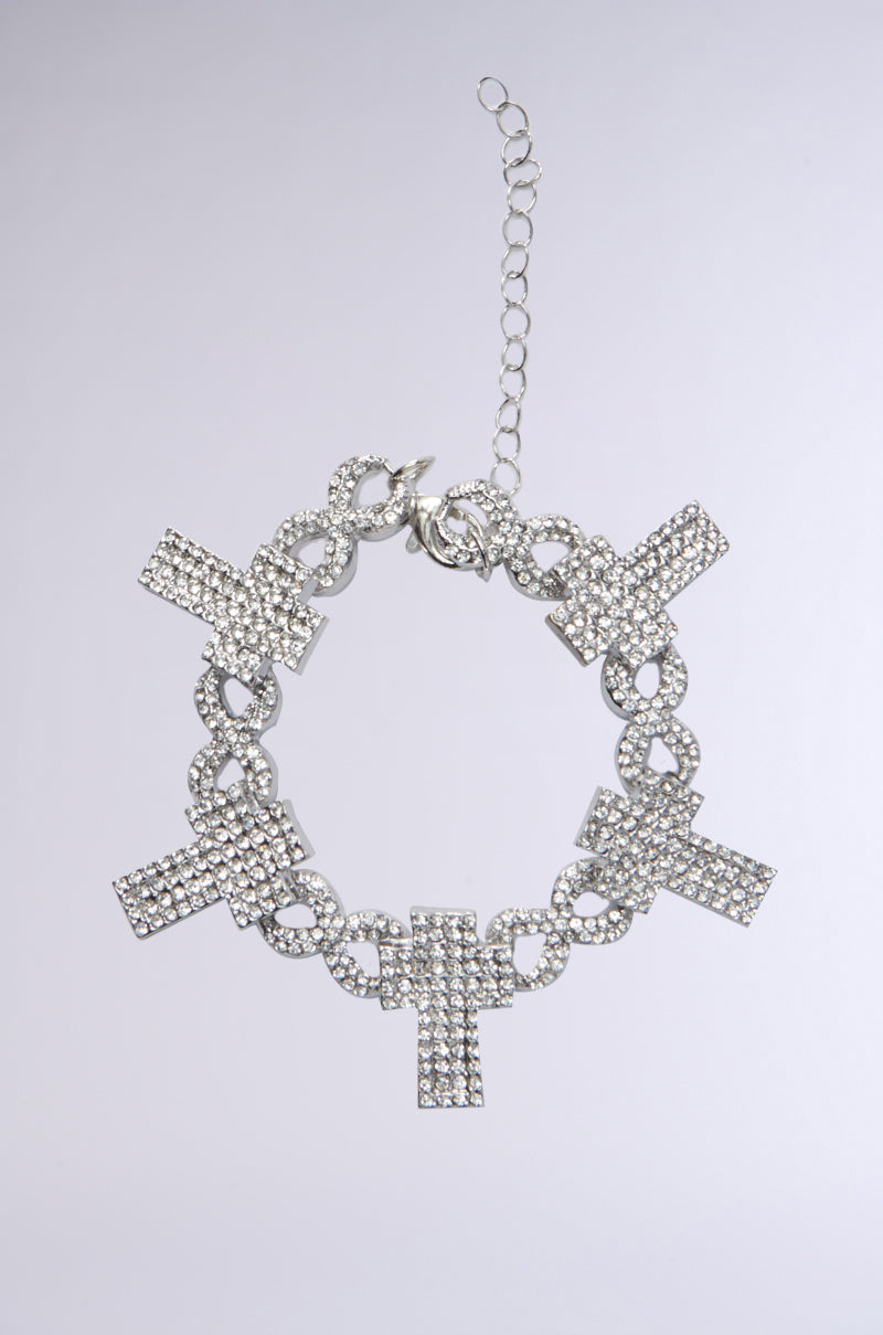 The CROSS MY HEART BRACELET features five oversized cross pendants embellished with rhinestones and small stones, displayed in a circle on a light gray background. 0