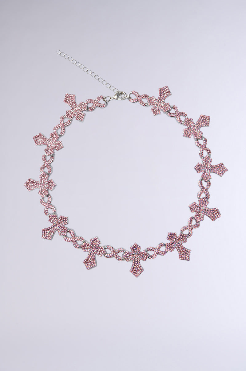 The ICED OUT CROSS NECKLACE is a pink rhinestone beaded choker with multiple cross pendants spaced around the chain, finished with an adjustable lobster clasp and shown on a plain light background.