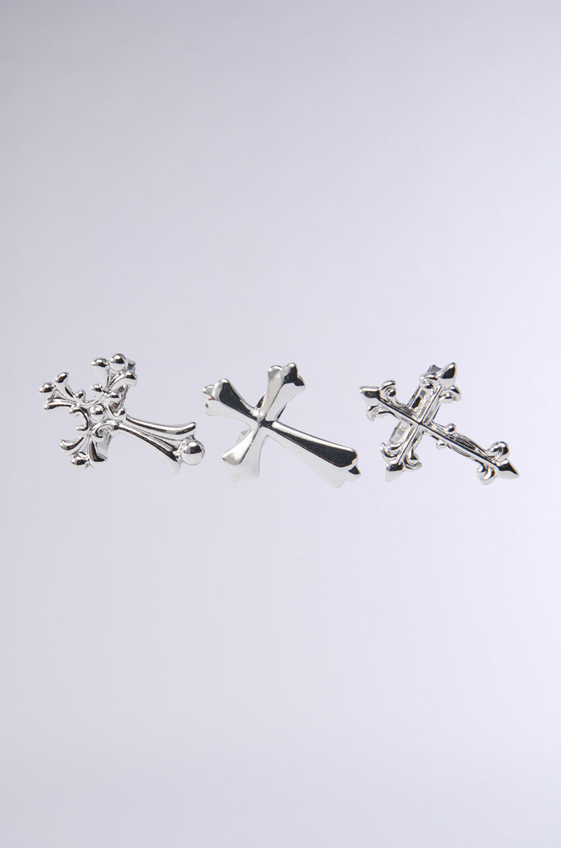 The CROSS MY HEART RING SET features three ornate silver rings set against a light gray background. Each ring has intricate detailing and unique designs, with the central one slightly larger, capturing attention with its elegance.