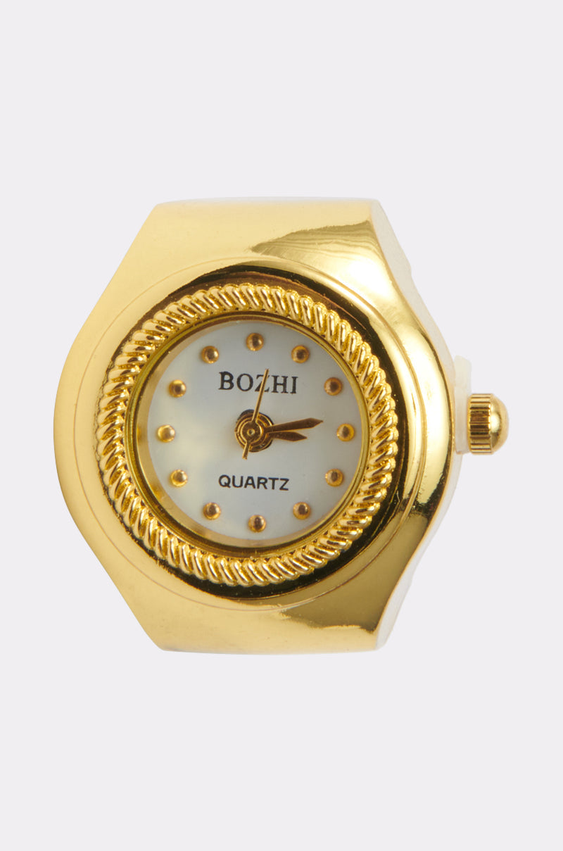 The WHATS THE TIME RING is a faux gold-toned quartz timepiece ring featuring a round white face, gold hour markers and hands, set in an ornate bezel—making it a striking statement accessory. 0