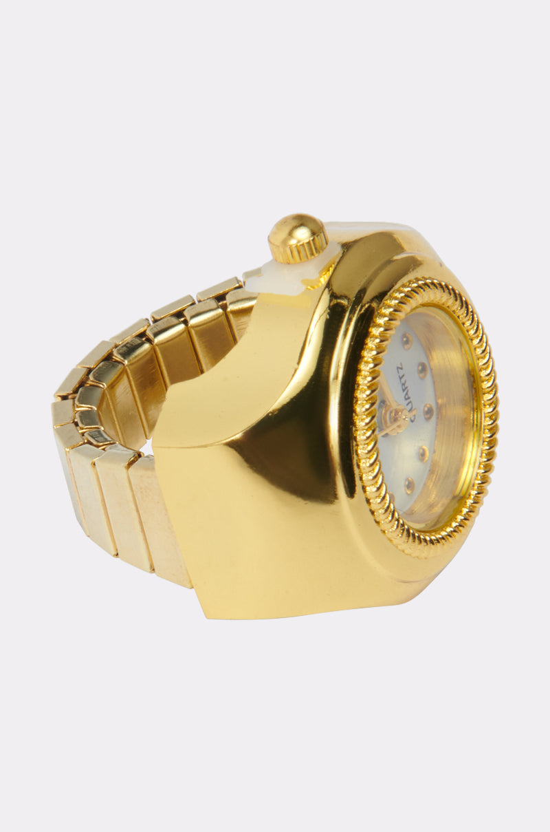 The WHATS THE TIME RING features a faux gold design with an oversized, textured bezel and prominent crown. Its thick band and small watch face create a bold contrast, making this statement ring a standout accessory. 2