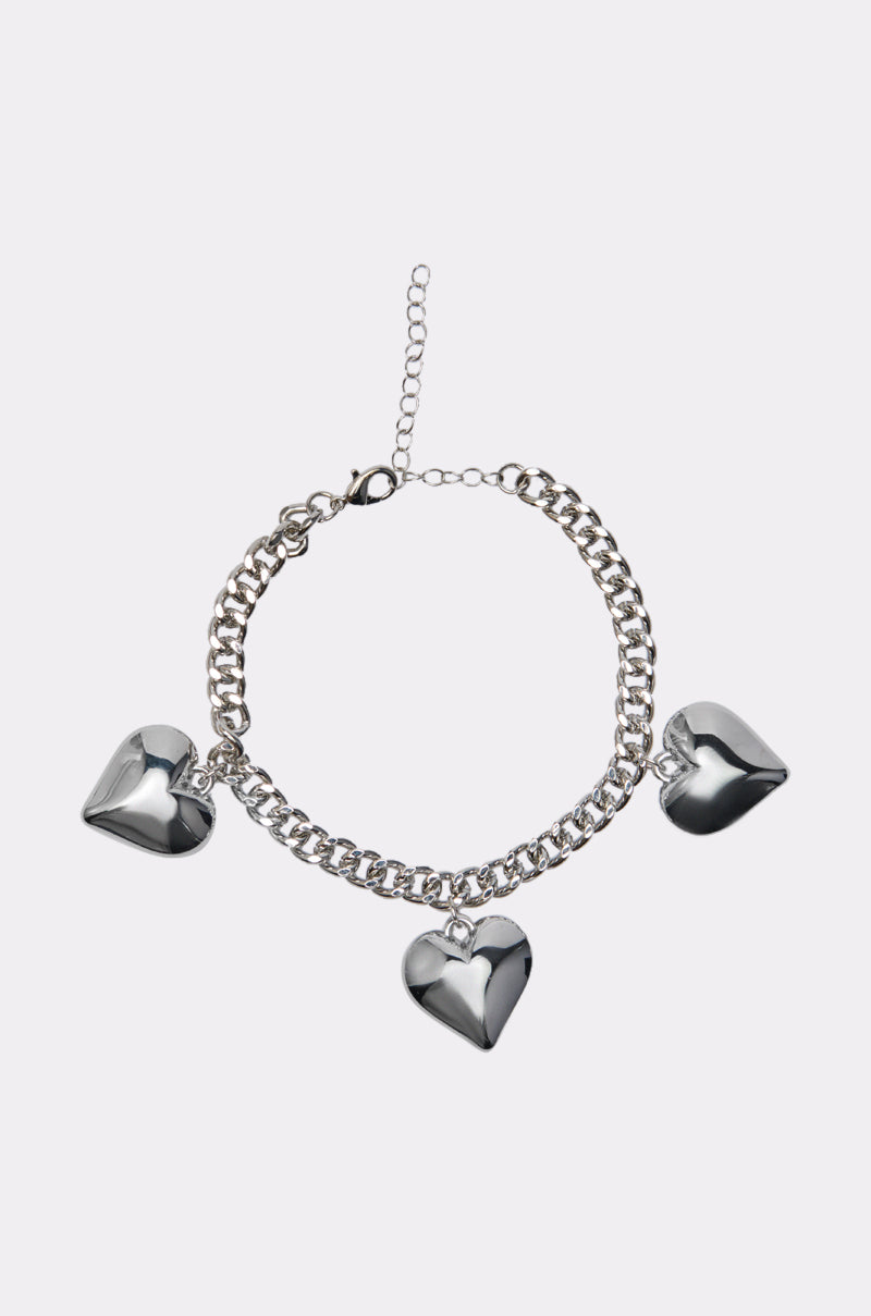 The OPEN YOUR HEART CHARM ANKLET, a silver anklet with three metallic heart-shaped charms and an adjustable clasp, is shown against a plain white background. 0