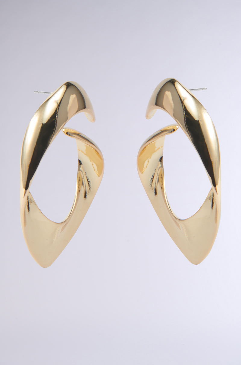Close-up of the LOVERGIRL EARRING, ideal for date night. These faux gold earrings boast a shiny finish and an abstract, twisting design set against a simple, light background. 5