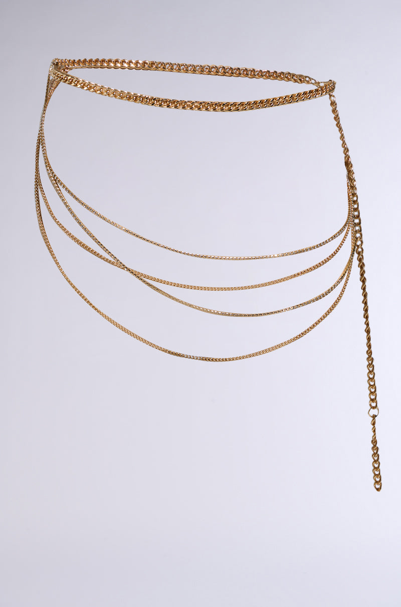The CHAINZ 4 DAYS BELT IN GOLD features a delicate faux gold chain with multiple cascading layers. Its slim, adjustable fit adds sophistication, with rhinestone links that sparkle subtly. The longest chain creates a chic asymmetrical look against neutral backgrounds. 2