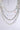 The TAKE A NOTE SILVER NECKLACE features layered chunky silver chains with various link sizes, accented by pearls and colorful gemstone beads—blue, green, and red—creating a striking multi-layered look on a light gray background.