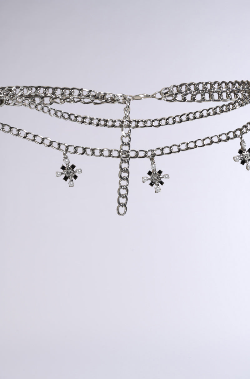 The DON'T CROSS ME BELT IN SILVER features layered chains with star pendants and gemstone touches, set against a white background, making it perfect for festivals. 4