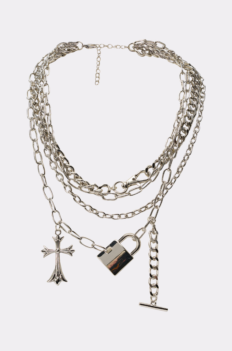 The HEART ON LOCK NECKLACE features layered chains with a lock and cross pendant in mixed styles, ideal for statement streetwear. Shown on a plain white background. 0