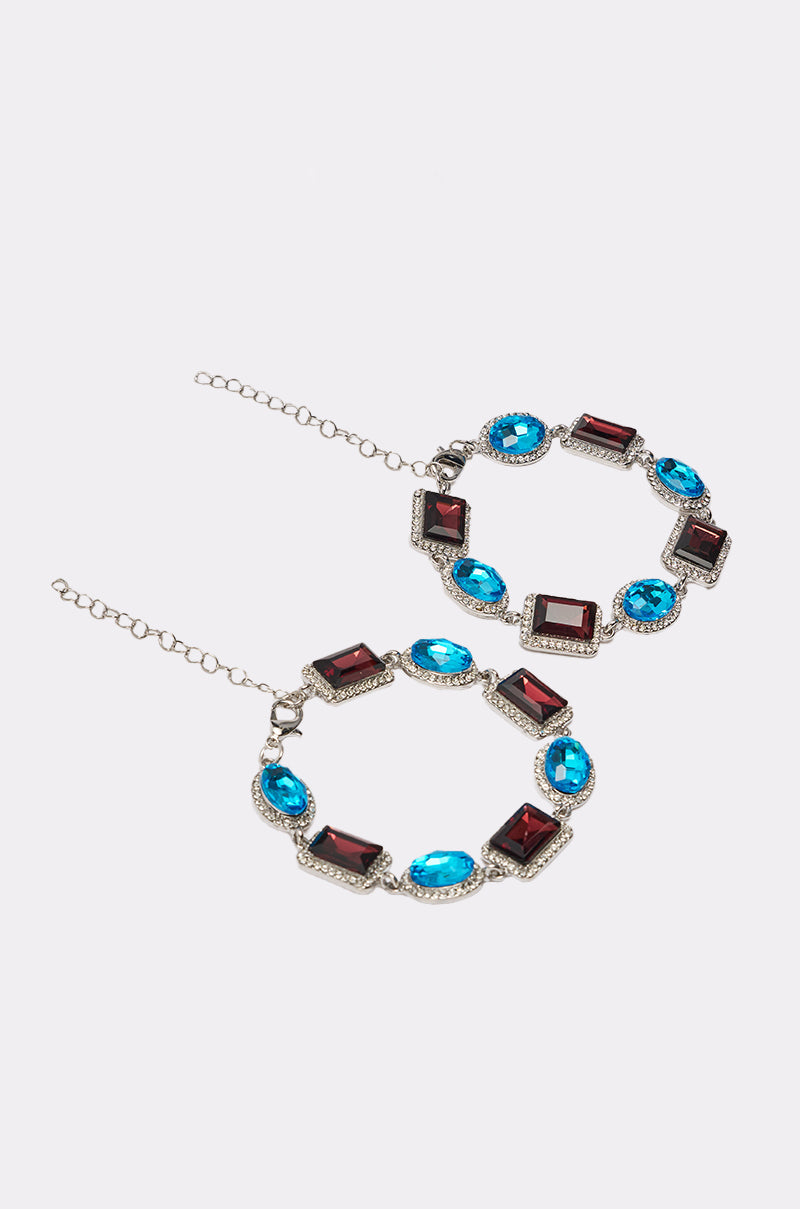 The CHOCOLATE WONDER BRACELET SET features large circular bracelets with alternating red rectangular and blue oval gems set in silver, rhinestone trim, and delicate chain-and-clasp closures. 2