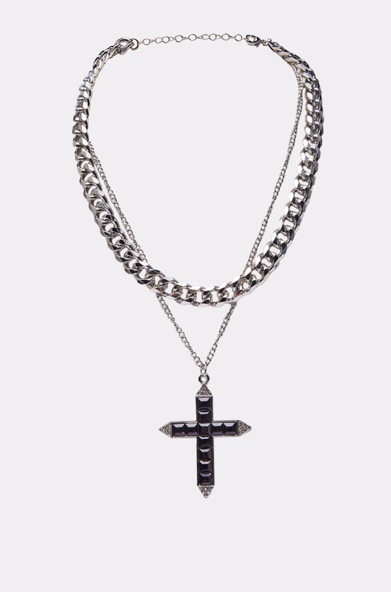 The KIM NECKLACE is a silver layered necklace with a thick curb chain, a thinner chain, and a striking black gemstone cross pendant with silver detailing, elegantly presented on a plain white background. 0