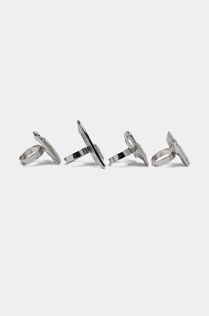 The TRUDY SILVER RING SET features four silver-tone rings, each with an oval-shaped, textured top, arranged upright in a row against a plain white background. 4