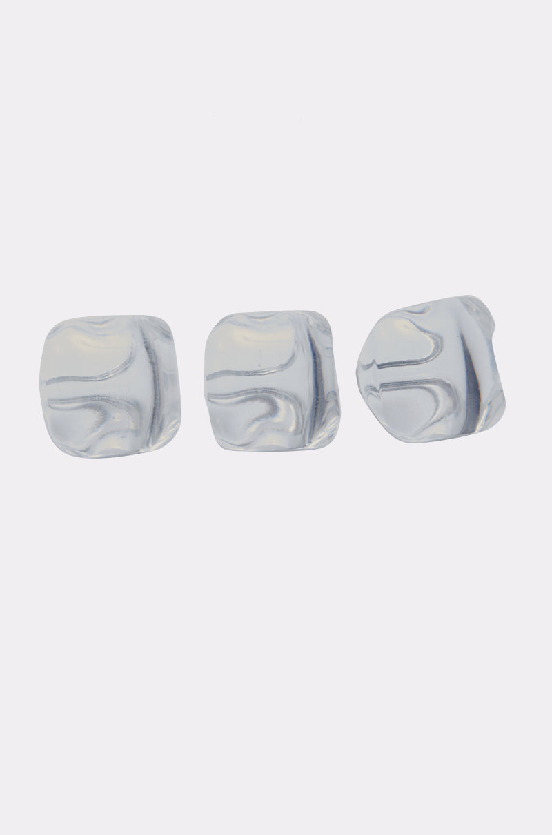 Three clear ice cubes are lined up on a white background, echoing the cool elegance of the DIRTY MARTINI RING SET’s chunky resin bands. 1