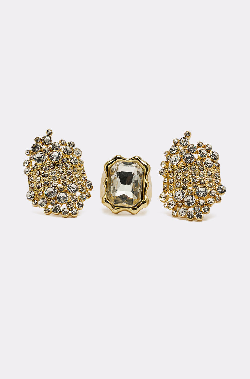 The CAN YOU NOT RING SET features gold-tone jewelry with two ornate beaded earrings adorned with clear stones and a matching crystal ring showcasing a large rectangular faceted gem, all shown on a white background. 0