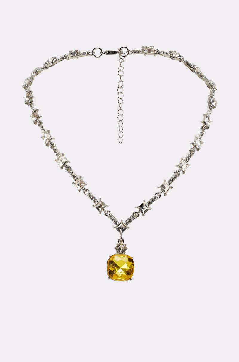 The LUXE KATE NECKLACE features star-shaped silver links and a striking, square-cut yellow gemstone pendant, accented by sparkling crystals. 0