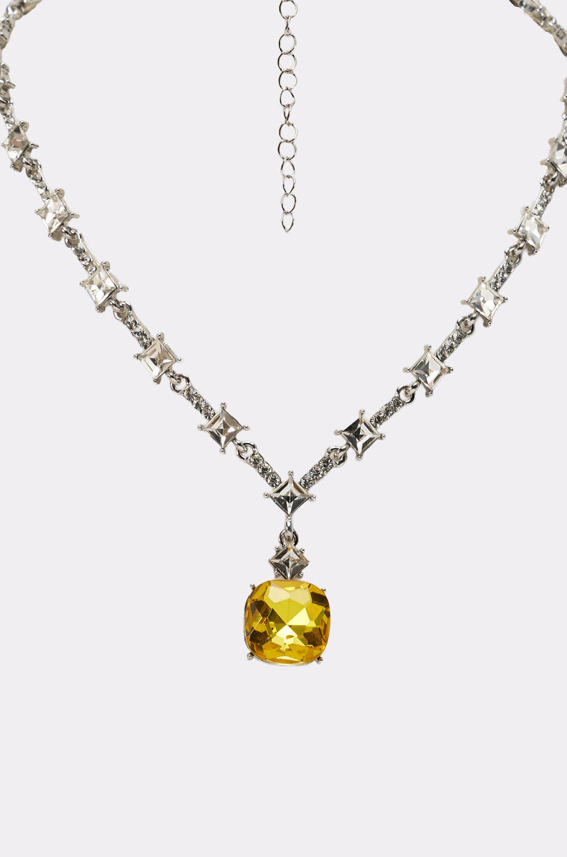 The LUXE KATE NECKLACE features star-shaped links, square-cut crystals, and a central yellow gemstone pendant for an elegant touch. 3