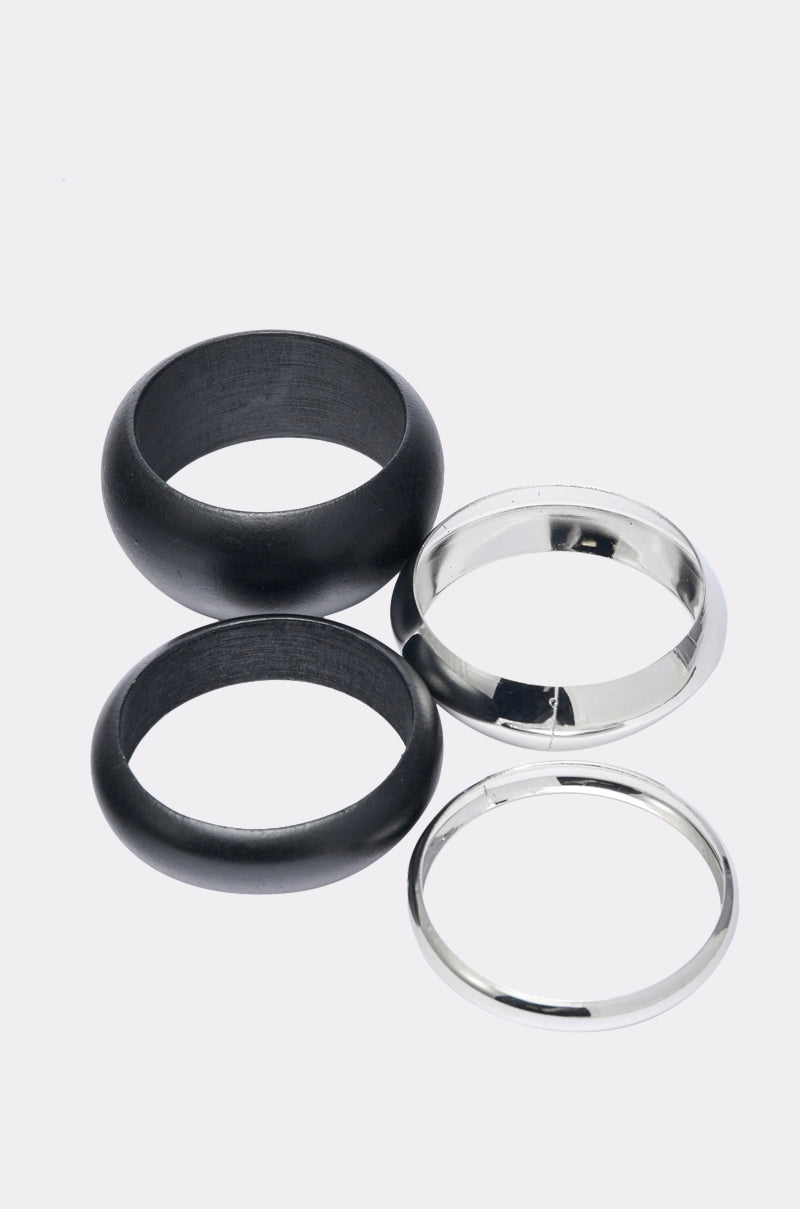 The MOD BRACELET SET features four rings on a light background: two thick black matte-finish rings and two shiny, slender silver-tone bangles for a sleek, modern look. 4