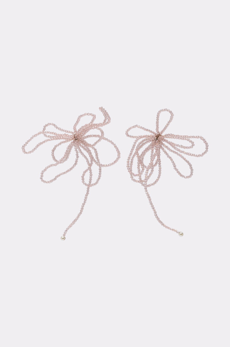 Two delicate, pale pink beaded strings form loose bows on a light background, each ending in a small bead—reminiscent of the GIRL PWR EARRING and adding a subtle, elegant twist to classic statement earrings. 2