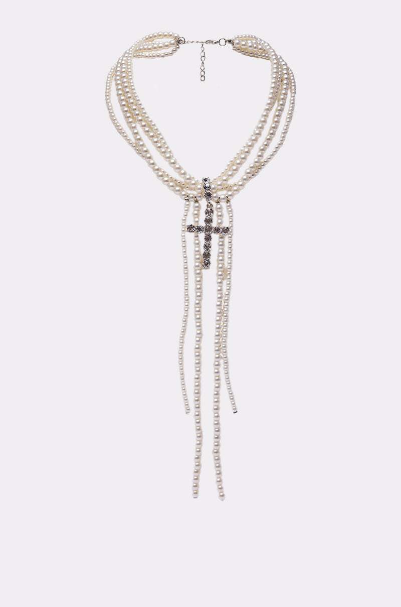 The CALL ME LATER PEARL NECKLACE is a statement multi-strand pearl necklace with a bold cross pendant and cascading pearl strands, elegantly shown on a plain white background. 1