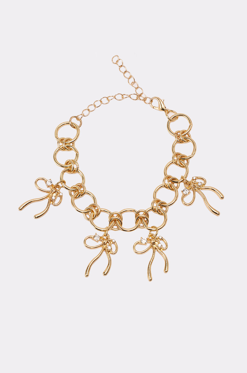 The BOW TIME CHARM BRACELET features large circular gold links and three bow-shaped charms, displayed on a plain white background. 0