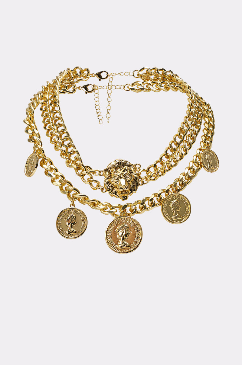 The AM WHO I THINK I AM NECKLACE is a gold statement piece featuring layered chains with round coin pendants and a central ornate medallion, displayed on a plain white background. 0
