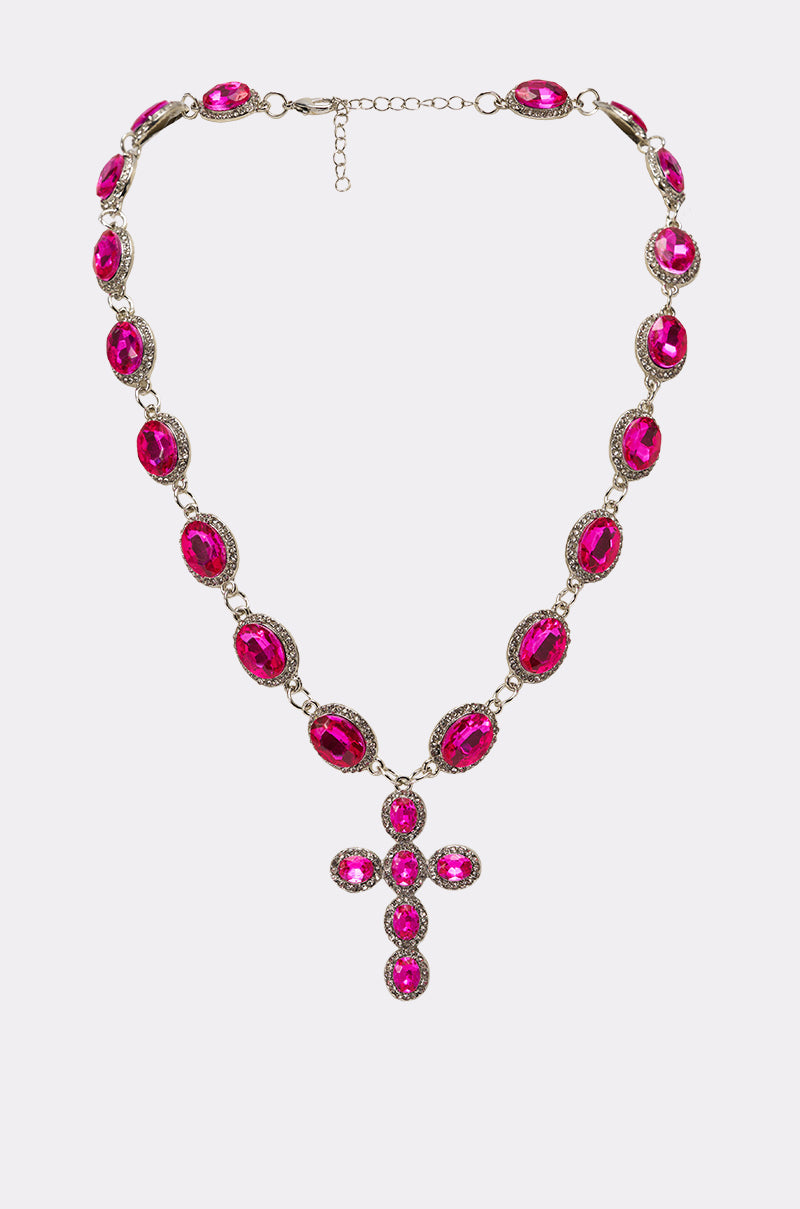 The NELLY NECKLACE showcases vivid hot pink oval rhinestones in gold crystal frames, finished with a matching cross pendant embellished in the same striking stones. 1