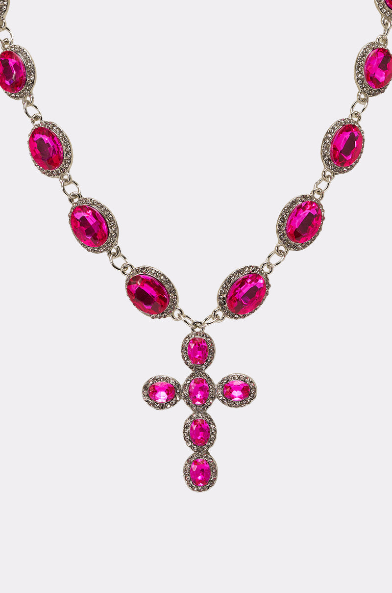 The NELLY NECKLACE features hot pink oval rhinestones set in silver with a matching cross pendant embellished with smaller stones, creating a dazzling statement against a white background. 4
