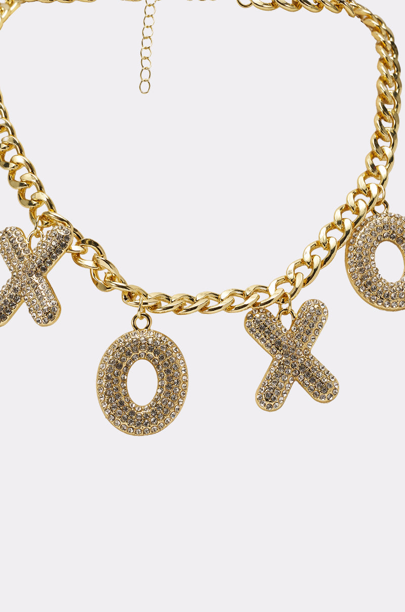 The KISSES NECKLACE showcases sparkling crystal XO charms on a gold pavé chunky chain, elegantly displayed against a plain white background. 6