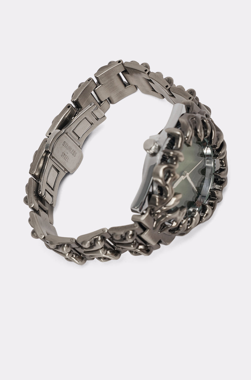 The IN MY VIBE WATCH features a silver-toned sculptural design with a chunky, intricately linked band and reflective face, shown from the back and side against a plain white background. 3