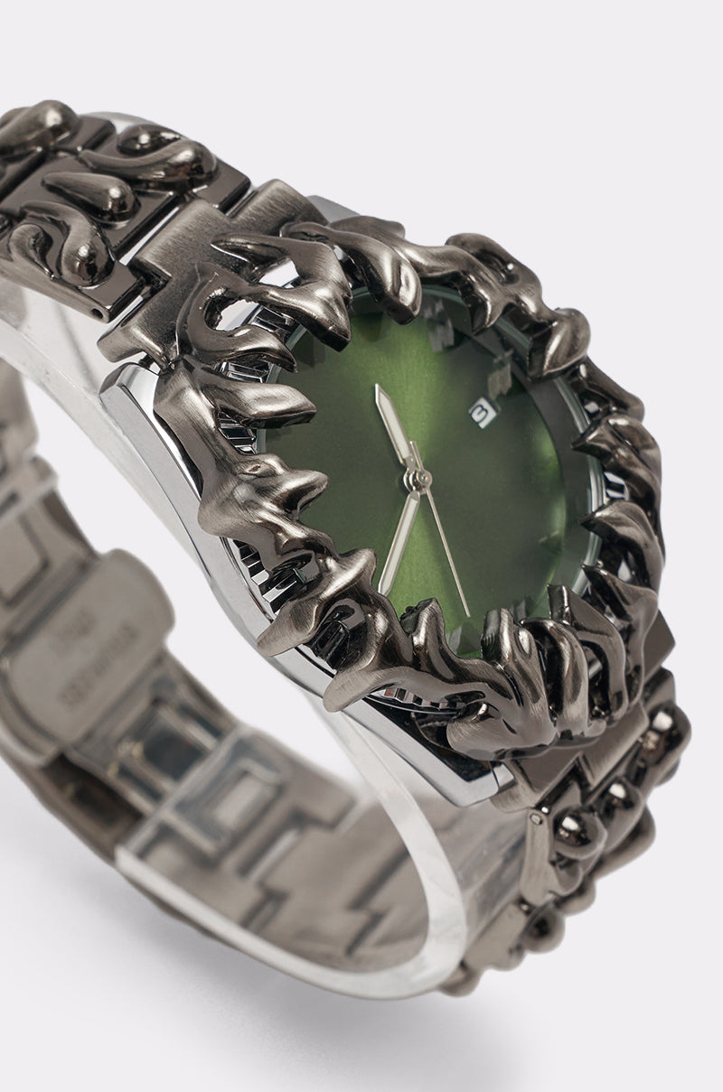 The IN MY VIBE WATCH features a sculptural metallic band inspired by claws or flames and a bold green dial with silver hour, minute hands, and hour markers. 4
