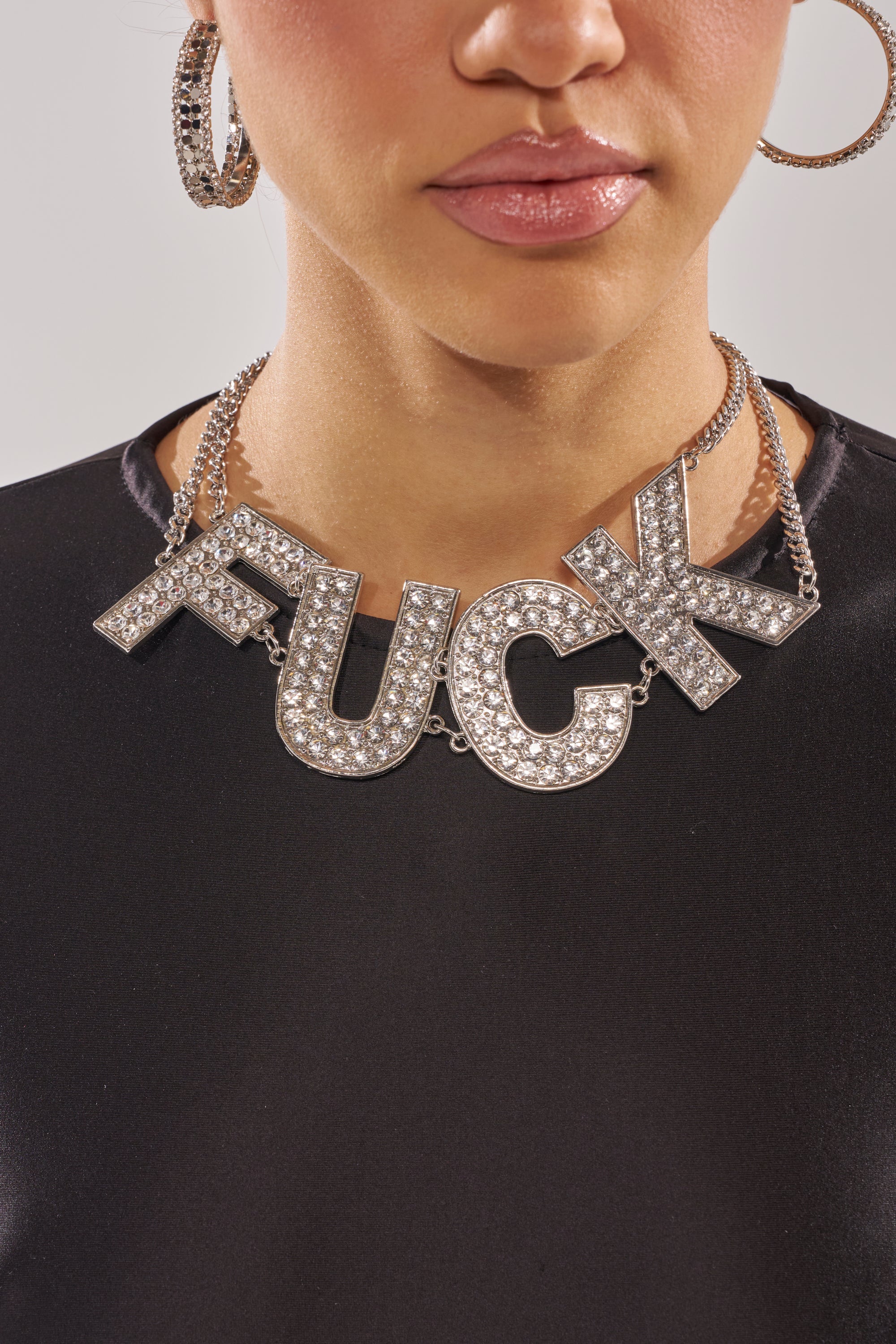 Wearing the ME NECKLACE, a woman adds a bold, sparkling touch to her look with this rhinestone statement piece. 1