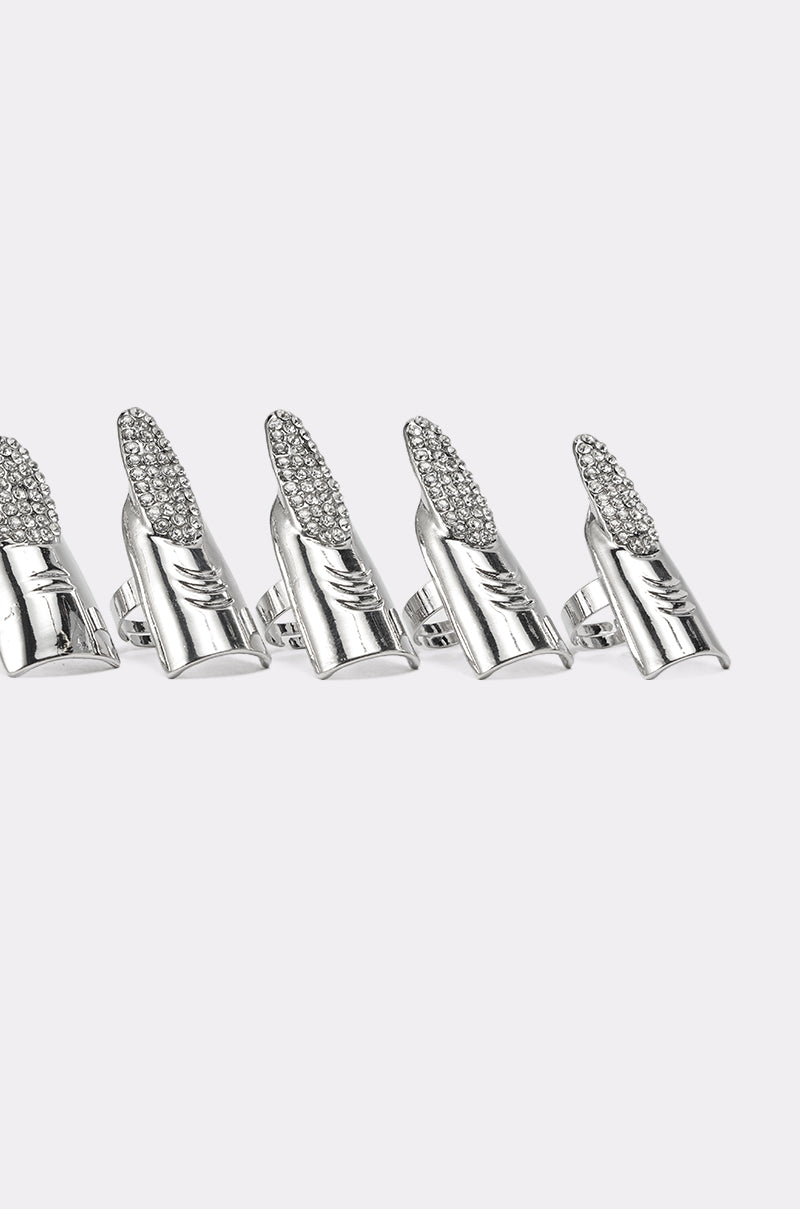 The STELLA RING SET features five silver finger armor rings with rhinestone pavé tips, arranged in a row on a plain light gray background—a bold statement set for standout style. 6