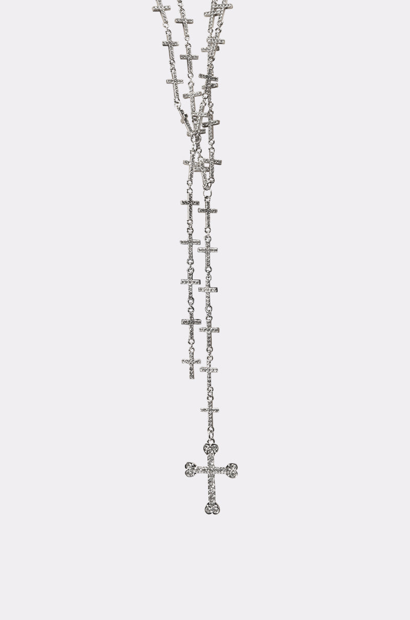 The TELL ME BOUT IT NECKLACE is a silver crystal cross necklace with multiple small cross pendants and a central, sparkling rhinestone cross pendant, displayed on a plain white background. 3