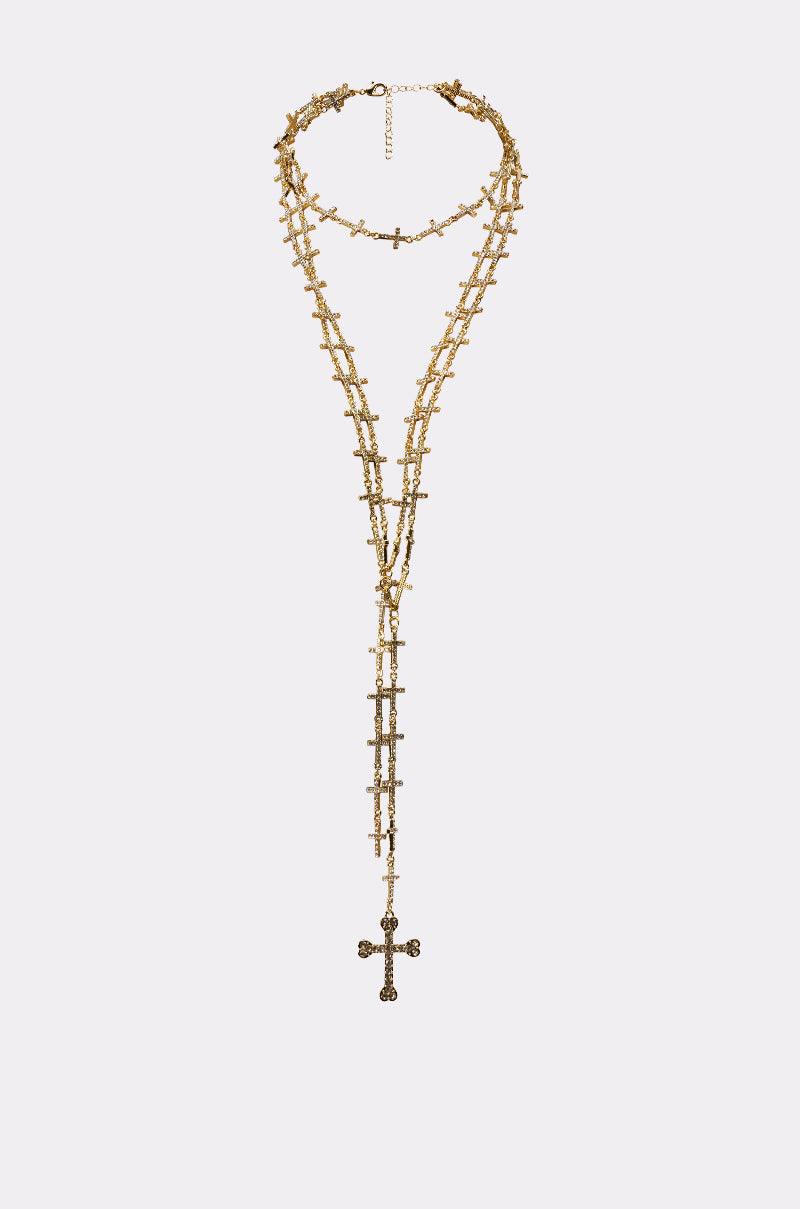 THE ONE NECKLACE features layered chains with small decorative crosses and a longer chain ending in a large ornate cross pendant, shown on a white background—a bold statement piece for any occasion. 1