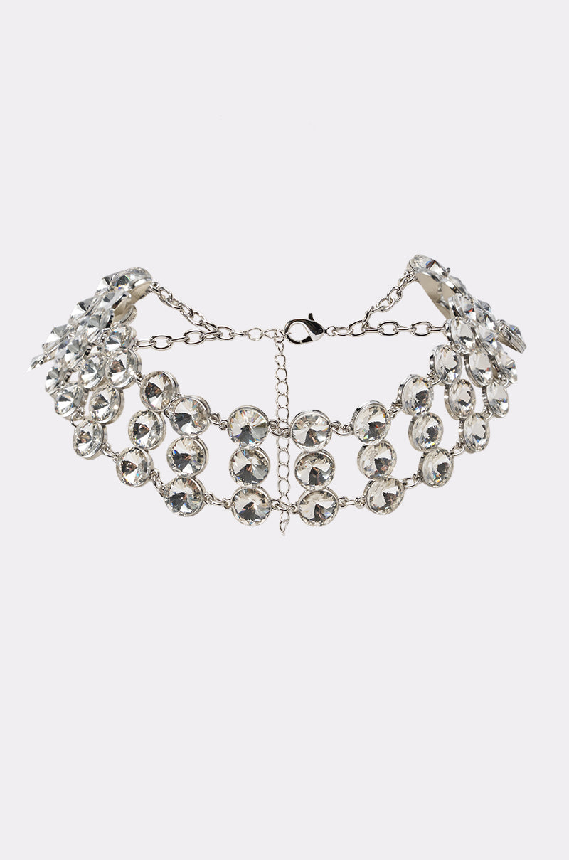 The GLAM LIFE NECKLACE is a silver-tone choker with multiple rows of large, clear rhinestones set in metal, finished with a chain and clasp closure—an ideal accessory for eveningwear.