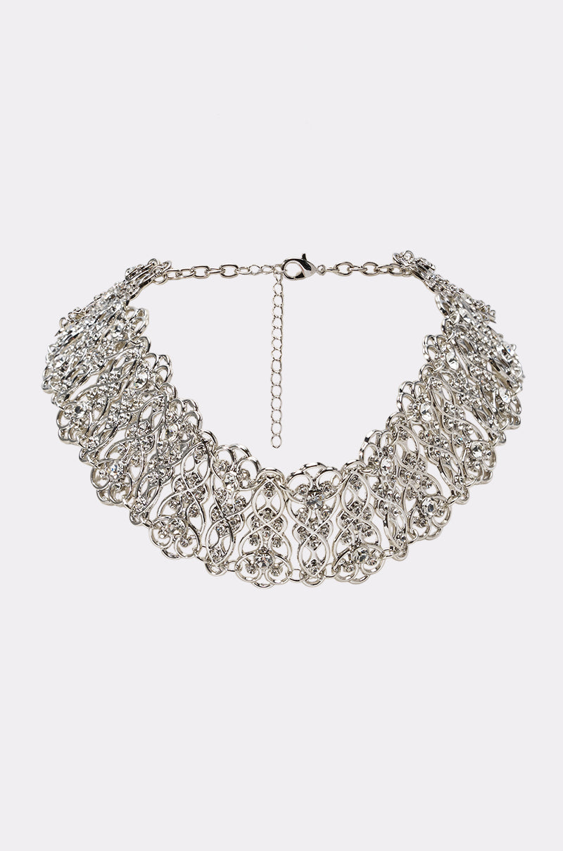The WRONG ERA NECKLACE is an ornate silver choker with intricate filigree lace patterns and an adjustable chain clasp, shown on a plain white background. This elegant piece adds vintage charm to any outfit.