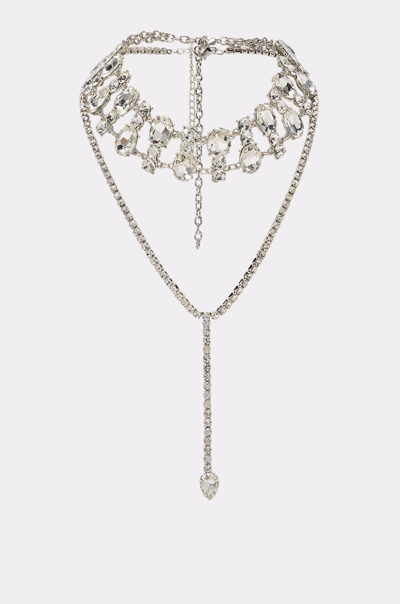 The DIAMOND LOVER LAYERED NECKLACE SET is a stunning silver two-piece set, featuring a rhinestone choker adorned with large, clear oval gemstones arranged in an elegant scalloped pattern, paired with a long single-strand drop ending in a teardrop-shaped gem. Beautifully displayed on a white background.