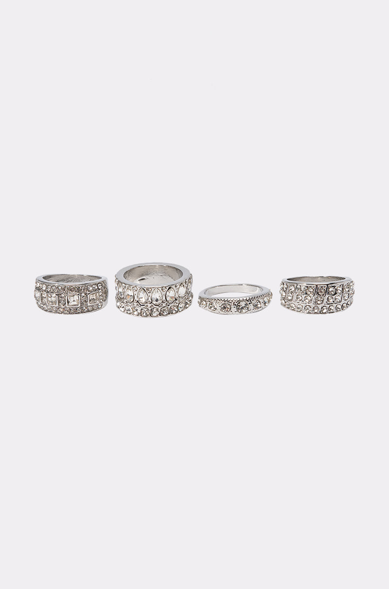 The ULTIMATE RING SET showcases four silver-tone rings with unique designs and sparkling rhinestones, arranged in a row on a white background—ideal for mixing textures and achieving a chic stacked look.