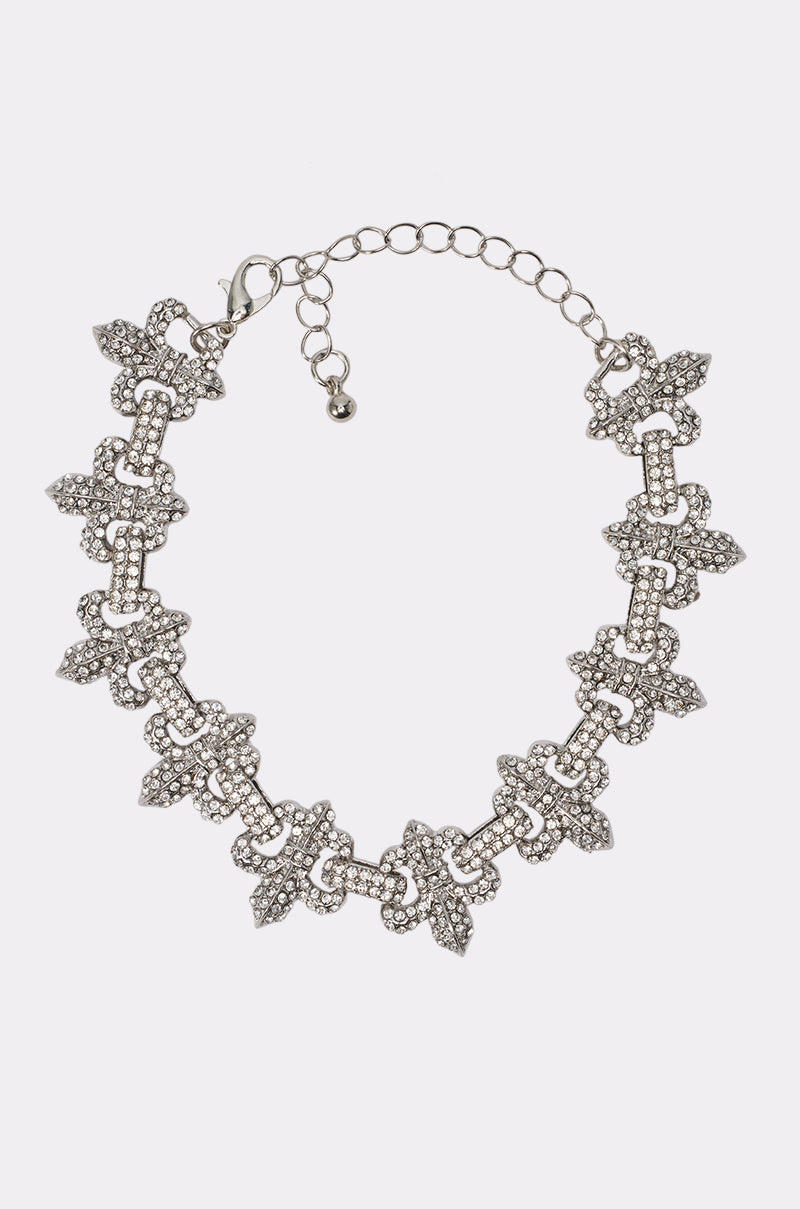 The IVY FLEUR DE LIS BRACELET features intricate, repeating arrow-shaped links adorned with small white crystals and an adjustable chain clasp—perfect for pairing with your favorite night-out jewelry.