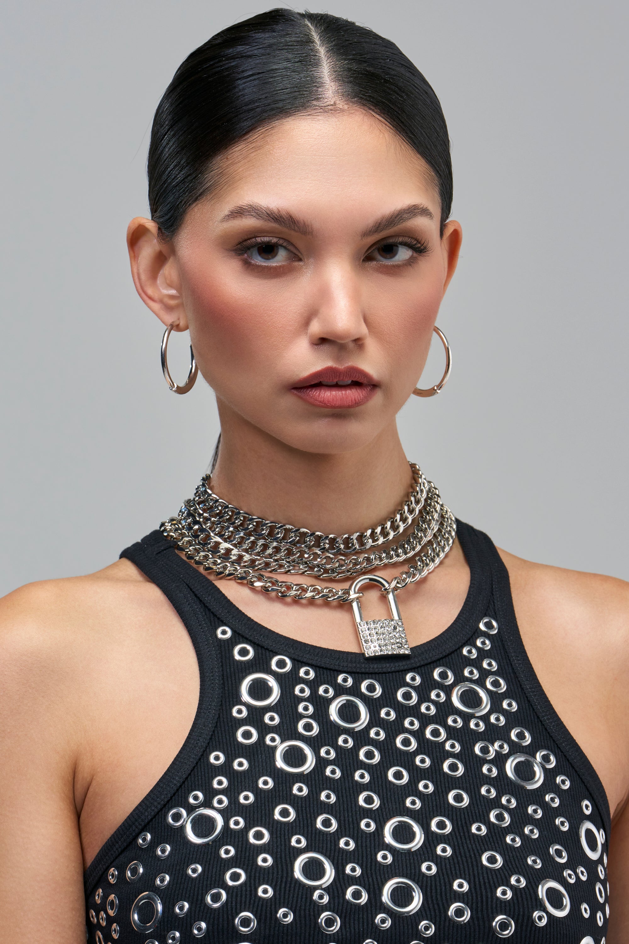 A model in a black tank top with metal eyelet details wears a layered, silver-tone rhinestone KEEP IT ON LOCK NECKLACE.
