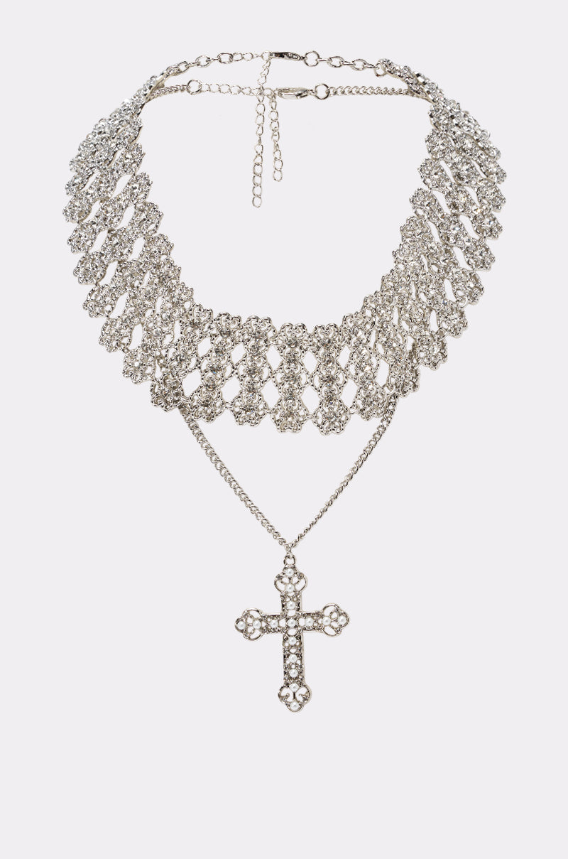 The INTENTIONS NECKLACE is a silver choker with a wide, intricate lattice design and an ornate cross pendant suspended from a delicate chain below the collar.