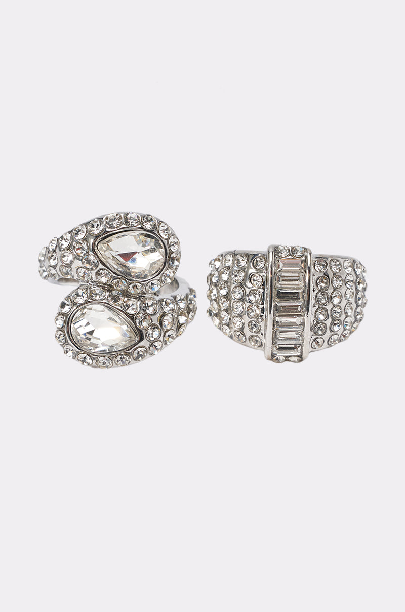 The ICE ME OUT RING SET includes two crystal-studded rings: one silver-tone ring with teardrop-shaped stones and another featuring a central row of rectangular rhinestones.