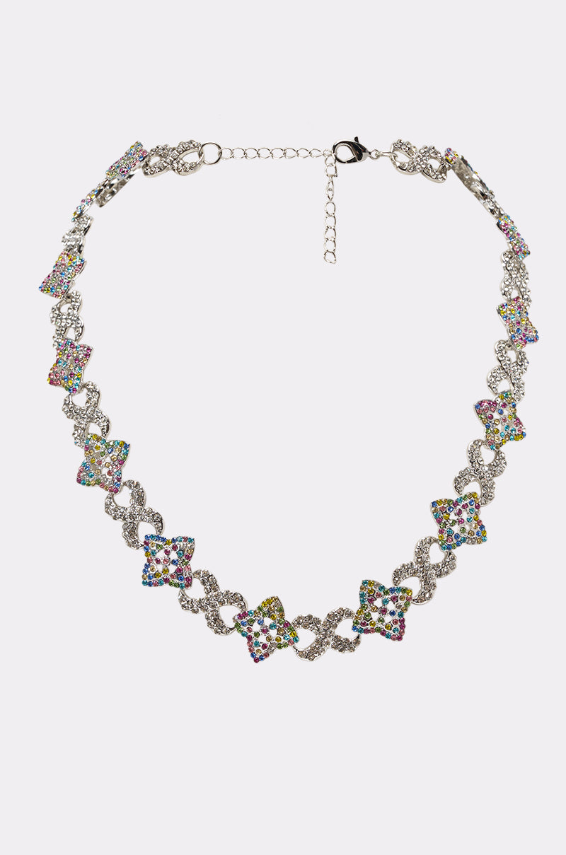 The VEGAS NECKLACE features alternating bow-shaped and twisted multicolor links, adorned with blue, green, pink, and yellow gemstones. It’s finished with an adjustable clasp for the perfect fit.