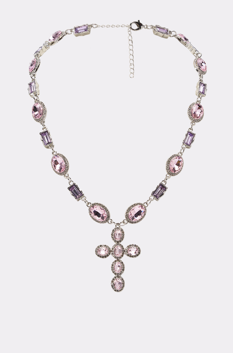 The DOIN ME NECKLACE is a vintage-inspired statement pendant featuring alternating oval and rectangular light purple gemstones, plus a bold cross pendant crafted from five oval pink gemstones.